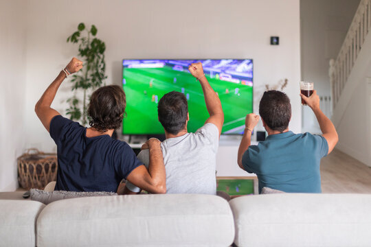friends watching football match at home cheering relaxed